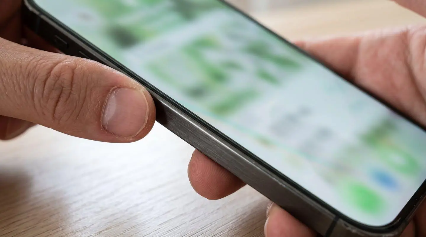 Gros plan sur une main tenant un smartphone affichant l'application mobile Société Générale, écran totalement flouté